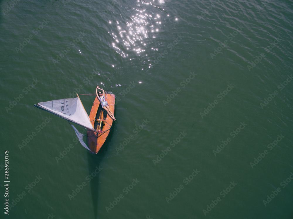 Aerial view of a woman in sailboat, top view of a lake landscape