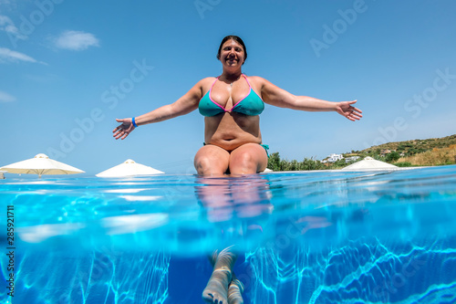 girl sunbathes on the edge of the pool in sunny day