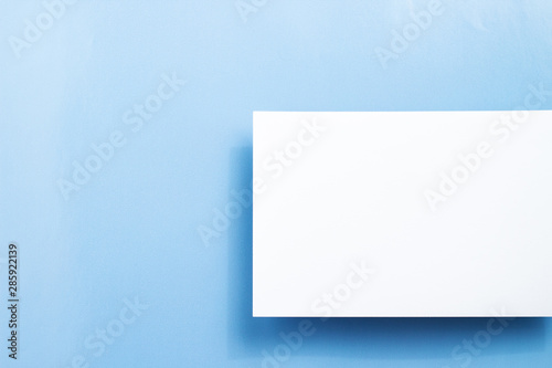Top view blank paper, white empty business card or flyer on blue background. Blank signboard with copy space area for text or slogan