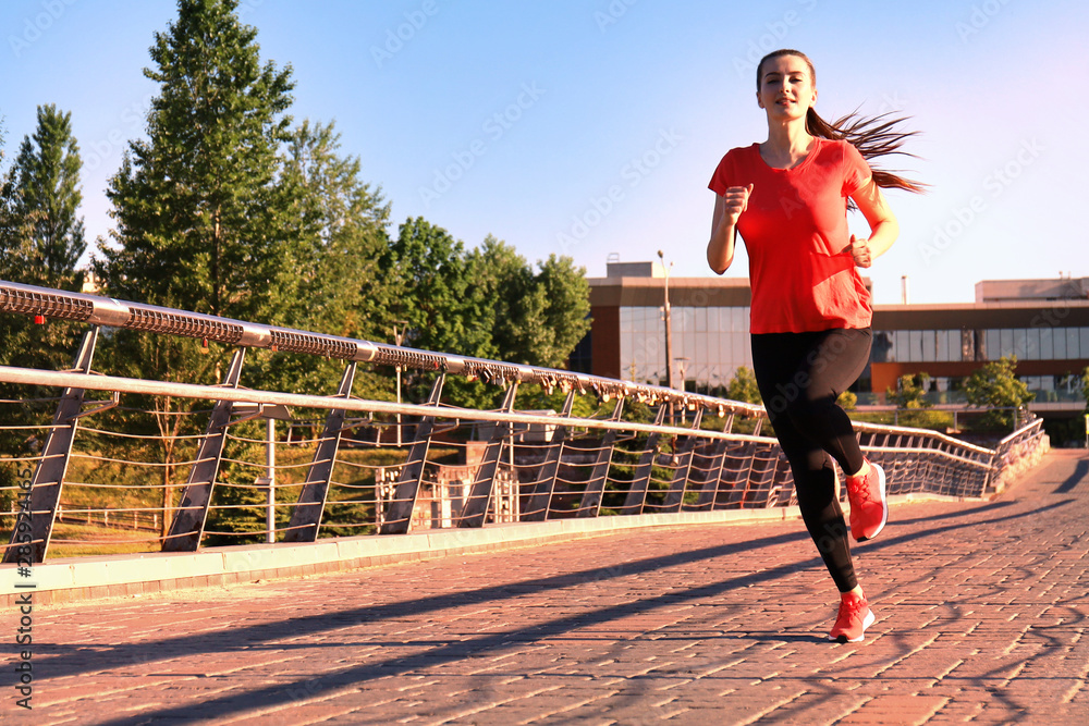 Obraz premium Beautiful young woman in sports clothing running while exercising outdoors.