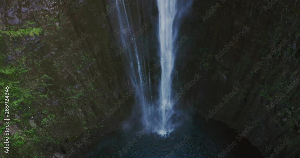 Aerial drone shot looking down on waterfall flowing into amazing natural pond, jurassic park concept