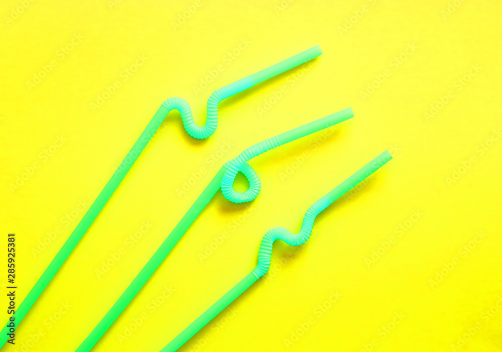 Green plastic cocktail tubes with a flexible part, due to which they can be twisted into a knot or in a zigzag, on a yellow background. Modern and trendy neon colors. Eco concept Green plastic cocktail tubes with a flexible part, due to which they can be twisted into a knot or in a zigzag, on a yellow background. Modern and trendy neon colors. Eco concept