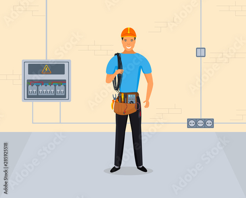 Professional electrician man standing in blue uniform with work tool bag holding cable and standing against the wall with electric panel, sockets and switch