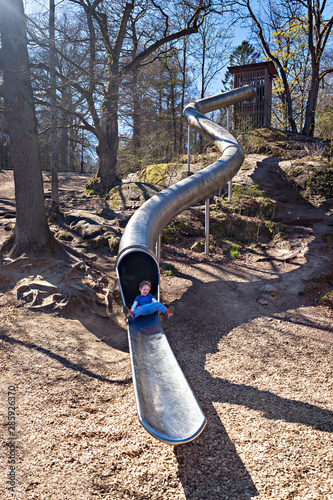Excited boy sliding on a metal slide in Slottsskogen Park