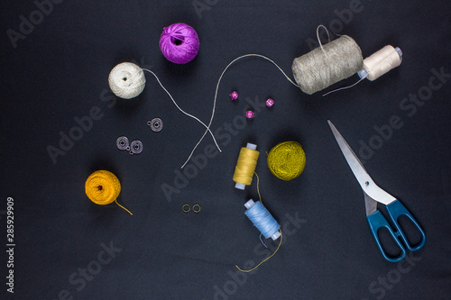 scissors and threads on a black background, top view
