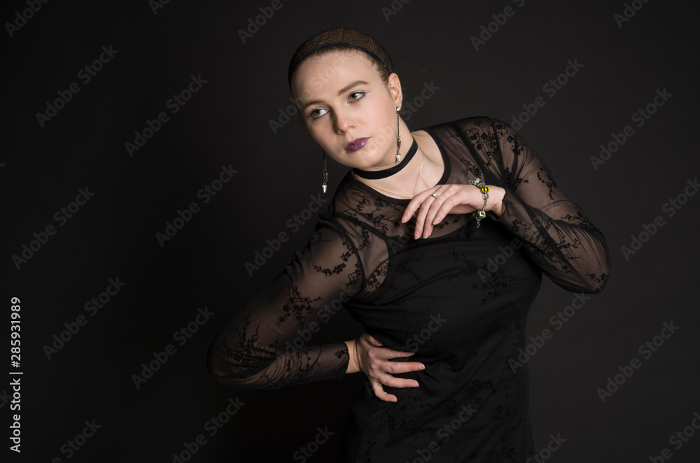 Beautiful young woman in black dress posing in studio with black background Beautiful young woman in black dress posing in studio with black background