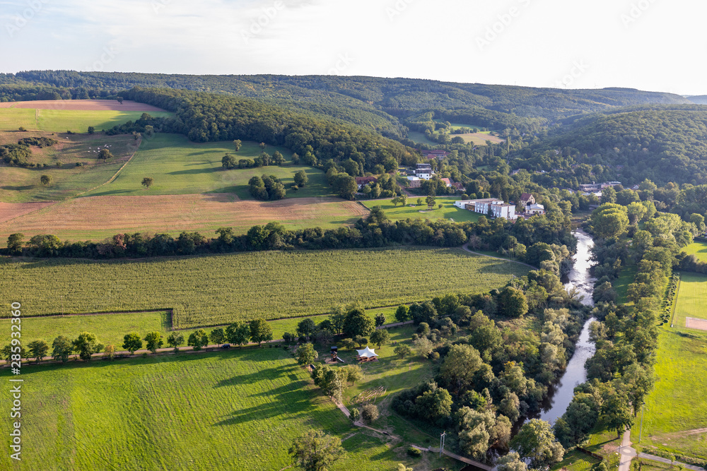 Aerial view at a landscape in Germany, Rhineland Palatinate near Bad Sobernheim with the river Nahe, meadow, farmland, forest and mountain range in the background