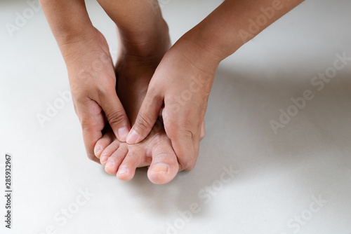 Woman massaging her painful foot and finger, healthcare and medical concept