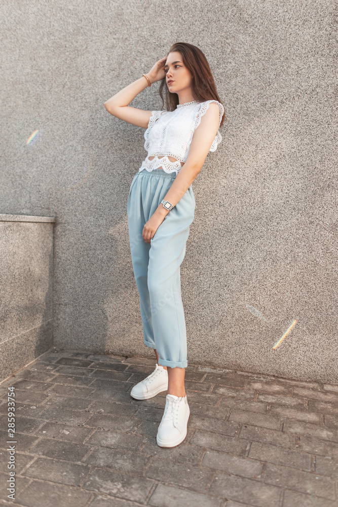 Young cute woman in elegant pants in a fashionable lacy t-shirt in