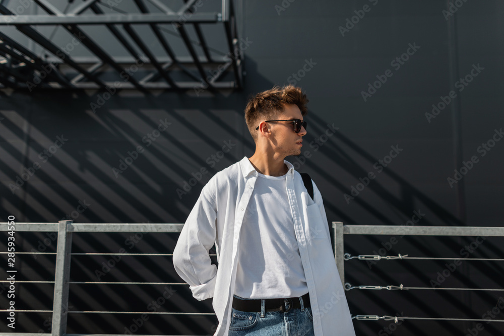 Young handsome model man with hairstyle in stylish white shirt in t-shirt in fashionable blue Young handsome model man with hairstyle in stylish white shirt in t-shirt in fashionable blue