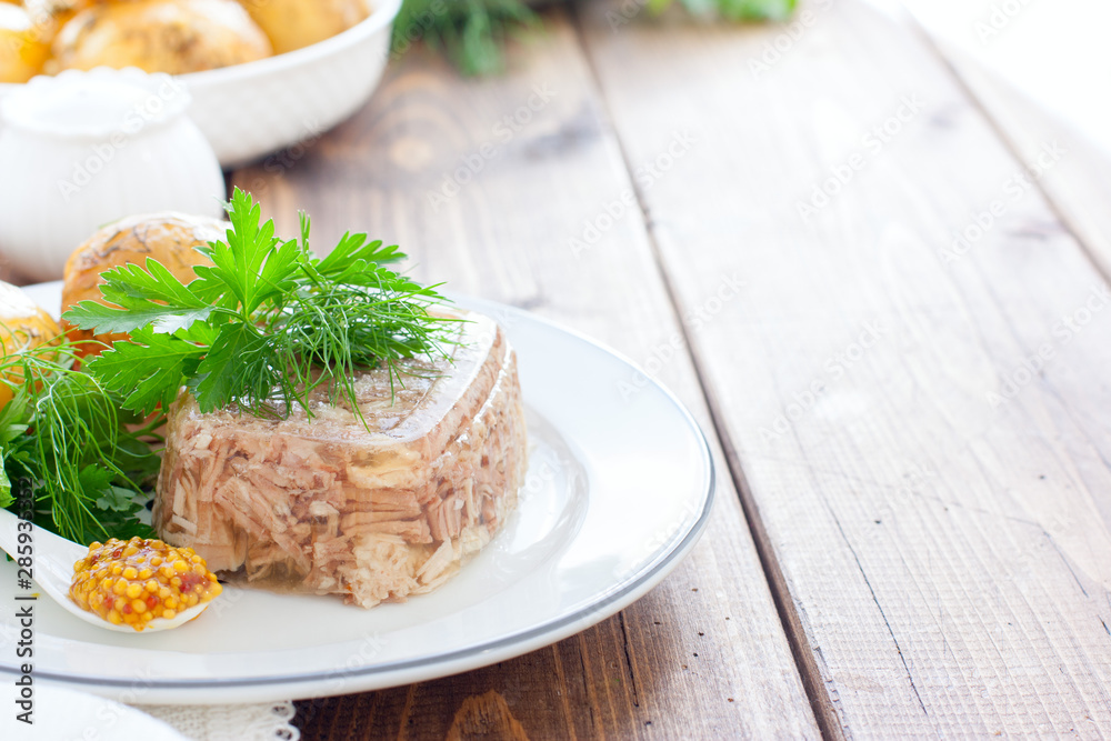 Homemade Aspic of turkey meat on a white plate with boiled potatoes and fresh herbs, horizontal, place for text
