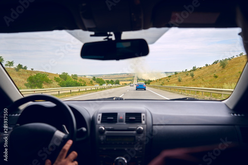 Fototapeta Naklejka Na Ścianę i Meble -  the driver behind the wheel in a car rides on the highway to another city