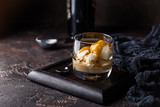 Ice cream with caramel topping and Irish cream liqueur in a glass over dark background.