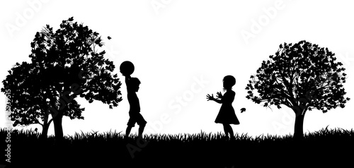 Two children, a boy and a girl, playing throw and catch in a park in silhouette