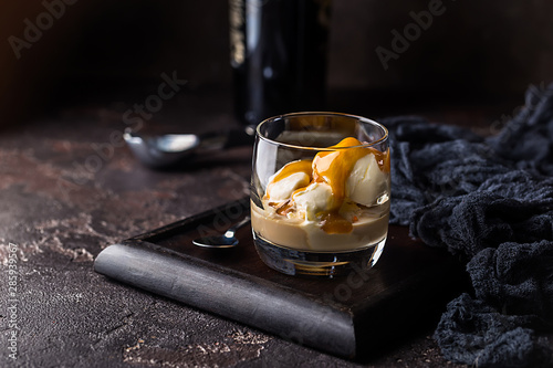 Ice cream with caramel topping and Irish cream liqueur in a glass over dark background. photo