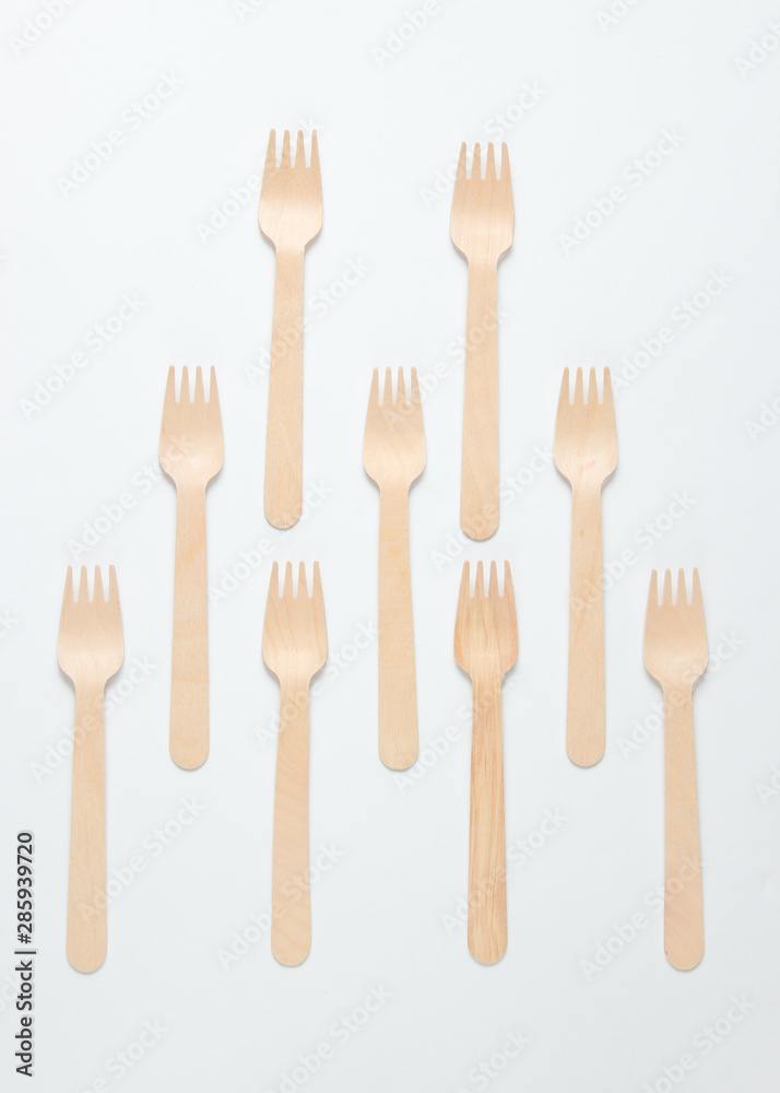 A lot of eco-friendly wooden forks on a white background. Minimalistic eco concept A lot of eco-friendly wooden forks on a white background. Minimalistic eco concept