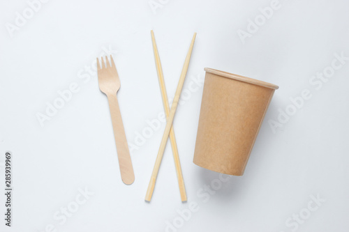 Eco-friendly cutlery. Chinese chopsticks, wooden fork, craft paper cup on white background. Minimalism eco concept.Top view