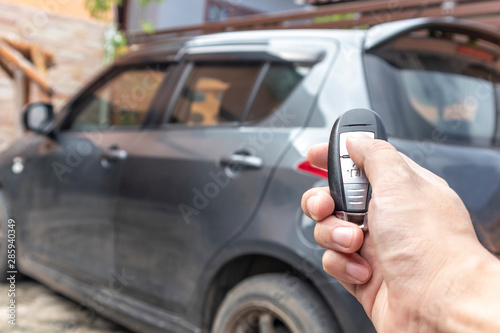 A man opening his car door with pushing button on control remote key.