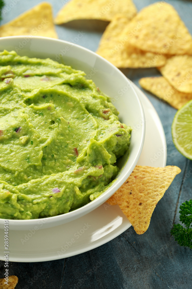 Bowl of fresh Guacamole with nachos chips and herbs. Healthy Vegan, Vegetables food. Bowl of fresh Guacamole with nachos chips and herbs. Healthy Vegan, Vegetables food.