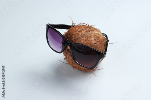 Creative fashion concept. Coconut with sunglasses on white background
