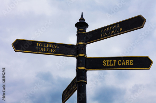 Word writing text Self Care. Business photo showcasing the practice of taking action to improve one s is own health Road sign on the crossroads with blue cloudy sky in the background