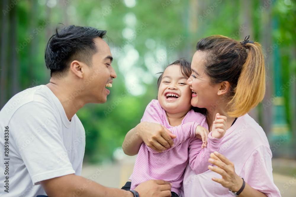 Fototapeta premium Happy child chatting with her parents in the park