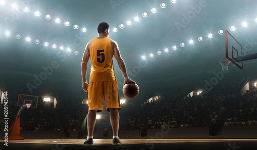 Basketball player in sports uniform on empty floodlit basketball court with the ball © TandemBranding