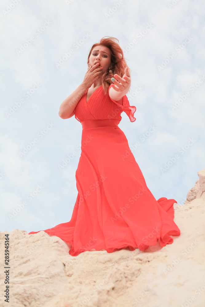 Young beautiful Caucasian girl stands on the mound of sand and looks down Young beautiful Caucasian girl stands on the mound of sand and looks down