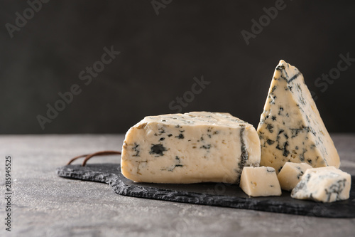 Slate board with delicious blue cheese on stone surface. Space for text