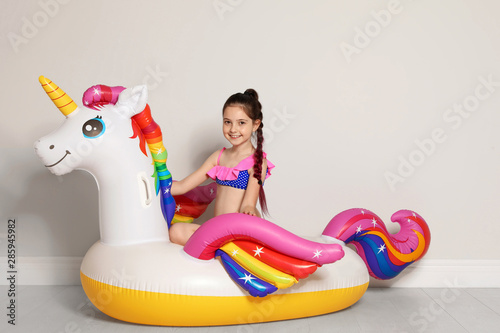 Cute little girl on bright inflatable ring near light wall © New Africa