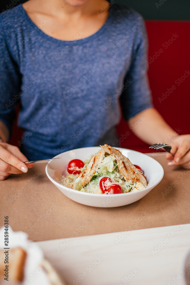 Woman's hands with Caesar salad on table in restaurant. Healthy food concept. Woman's hands with Caesar salad on table in restaurant. Healthy food concept.