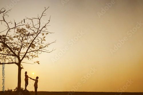 Romantic couple standing under a tree at sunset