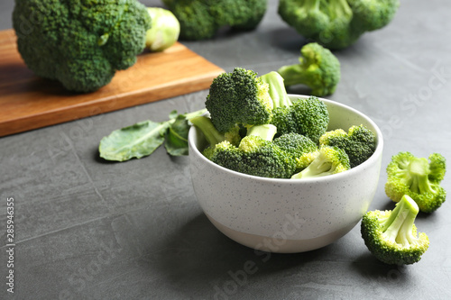 Bowl of fresh broccoli on grey table. Space for text