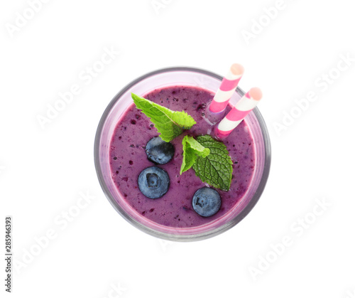 Glass of delicious blueberry smoothie with mint and straw on white background, top view