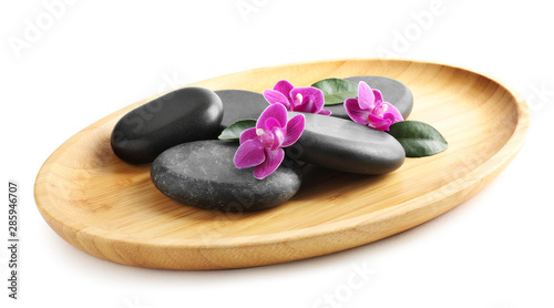 Wooden tray with spa stones and orchid flowers on white background