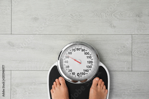 Woman standing on scales indoors, top view with space for text. Overweight problem photo