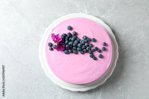 Plate with tasty blueberry cake on light grey table, top view