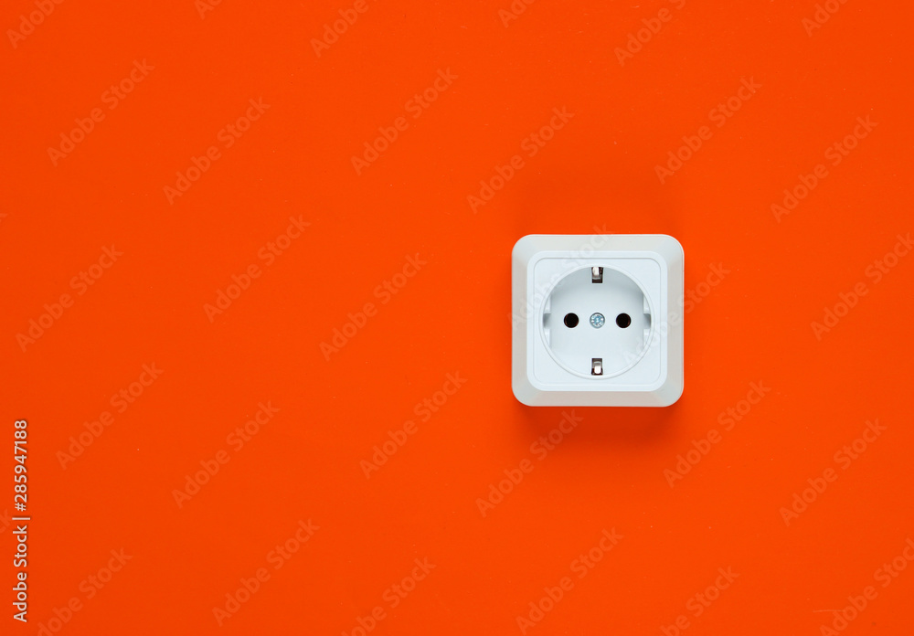 White plastic power socket on orange background. Wall with copy space. Minimalism White plastic power socket on orange background. Wall with copy space. Minimalism