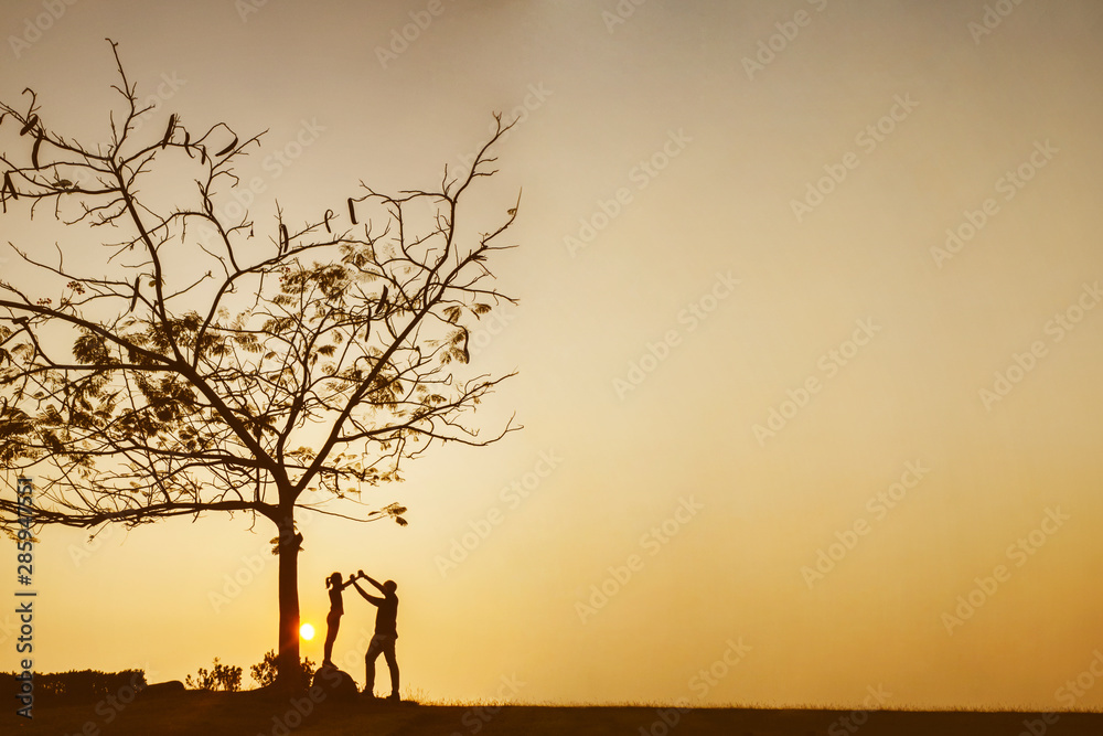 Silhouette of father and child at sunset time