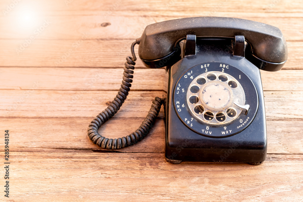 Retro rotary black telephone on wood table background. Old telephone with rotary dial. Retro rotary black telephone on wood table background. Old telephone with rotary dial.