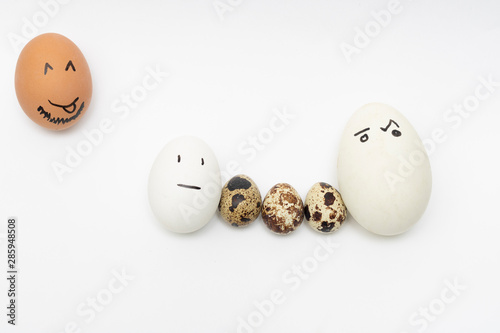 Chicken and quail eggs on a white background symbolize a family with children. Interracial marriage concept. Ludicrous images of human persons on chicken eggs.