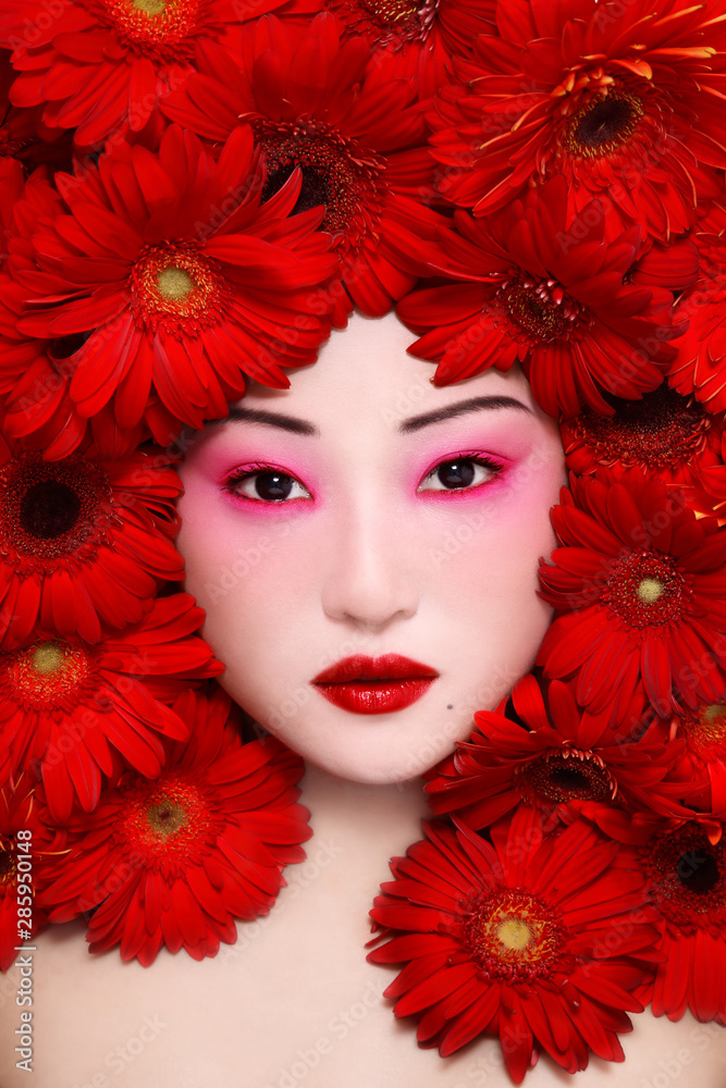 Vintage style portrait of beautiful asian girl with fancy makeup and red  flowers around face Stock Photo