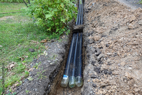 Three plastic water pipes in the pit, during repair work.