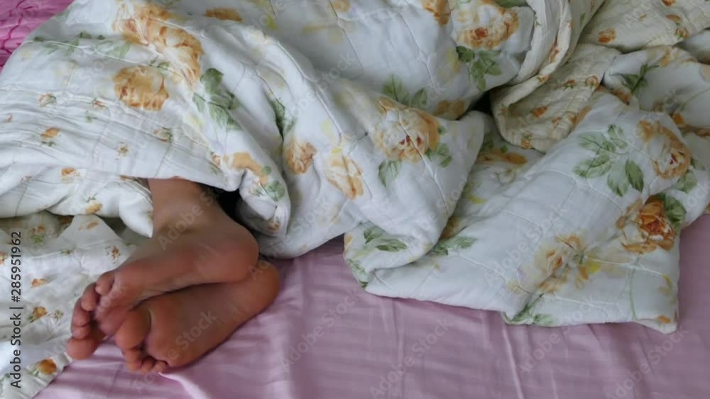 the person lying in bed is scratching his foot, the human feet coming out of bed, the person lying in bed is scratching his foot, the human feet coming out of bed,