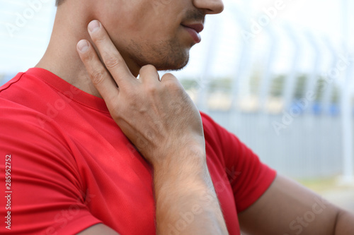 Canvas Print Young man checking pulse after training outdoors, closeup