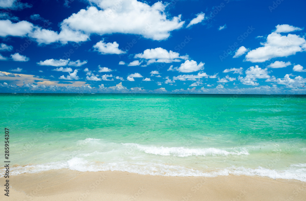 Bright scenic view of tropical Caribbean waves lapping the golden sands of a sunny beach under vibrant blue sky
