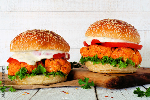 Cauliflower burgers with buffalo sauce against a white wood background. Healthy eating, plant based meat substitute concept. photo