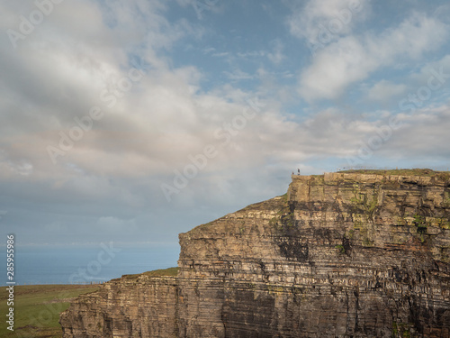 Cliff of Moher structure, and tourists standing on the edge. Concept safety, tourism, landmark.