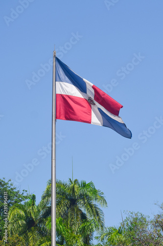 Flag of Dominican Republic (DR) waving in the wind with blue sky on background photo