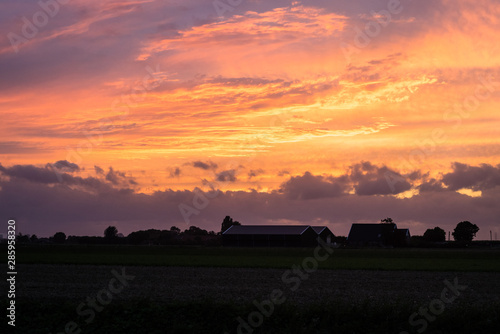 Colorful clouds over the silhouette of a farm at sunset